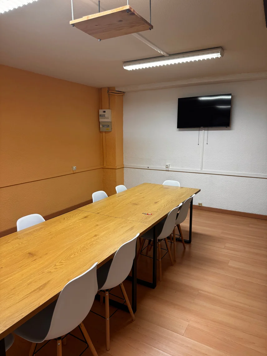La salle au mur jaune, équipée de tables modulables et d’un écran TV.